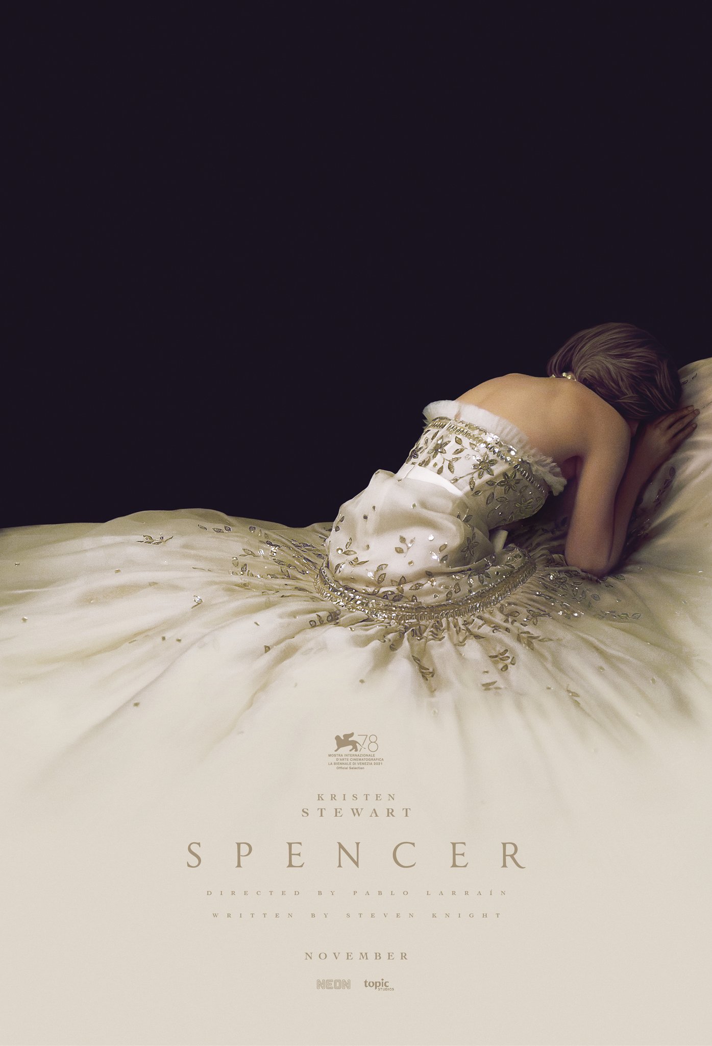 Movie poster for SPENCER. Showing Kristen Stewart (as Diana Spencer) curled up against her elegant evening dress on a dark background.